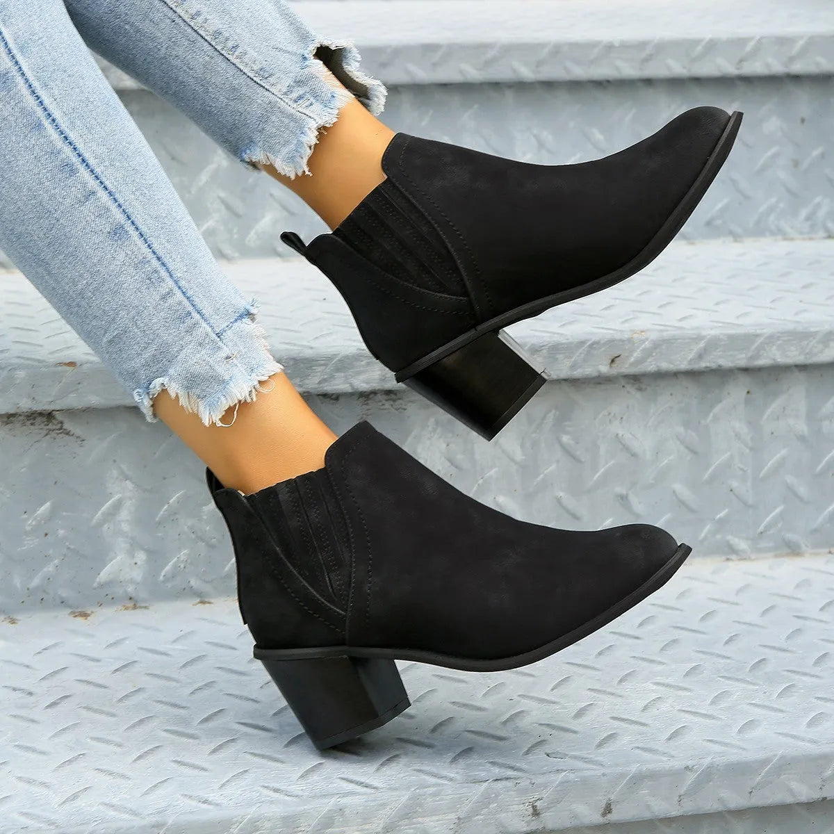 Black women's pointed toe ankle boots with a thick low square heel and slip-on design.
