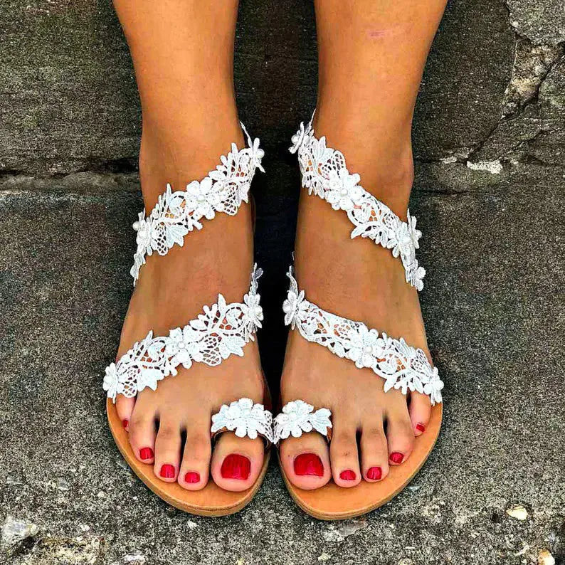 White casual flat sandals with rhinestone and floral decoration on a glossy PU upper.