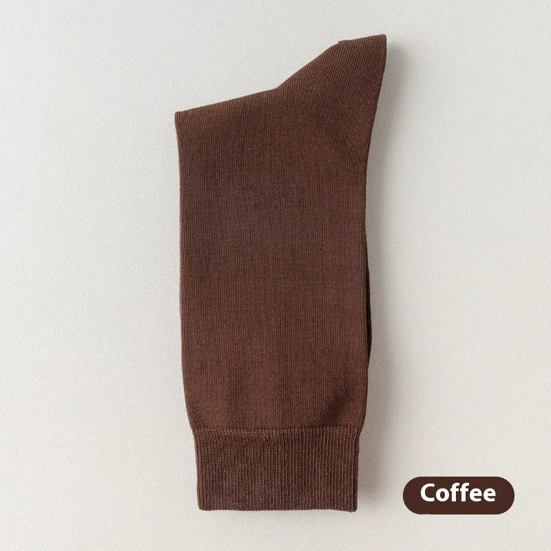 Pair of solid-colour men's mid-calf socks made from combed cotton on a wooden background