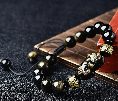 Handmade golden obsidian Pi Xiu bracelet with Chinese zodiac design on wrist.