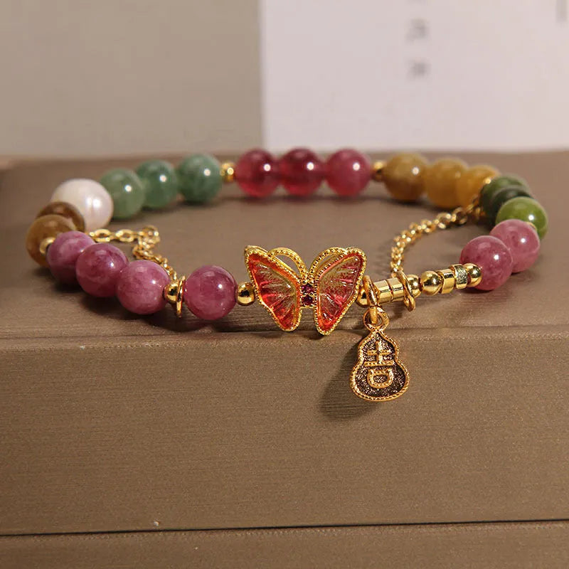 Close-up of a jade green tourmaline butterfly gourd charm on a brown agate bracelet for women.