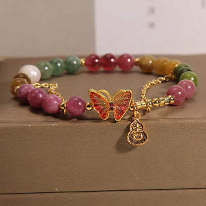 Close-up of a jade green tourmaline butterfly gourd charm on a brown agate bracelet for women.