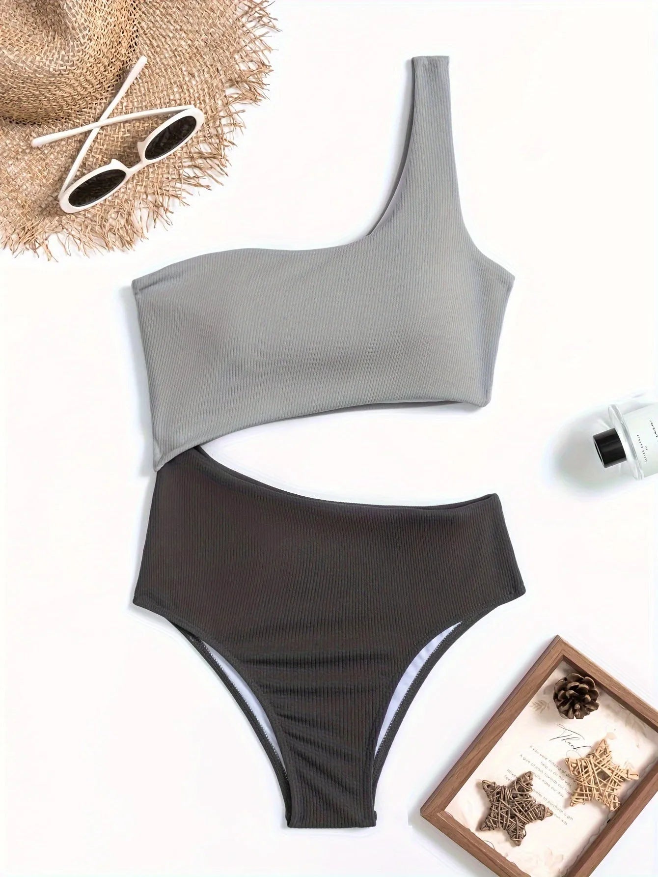 Light grey one-shoulder one-piece swimsuit on a mannequin, showing the single strap and solid colour design.