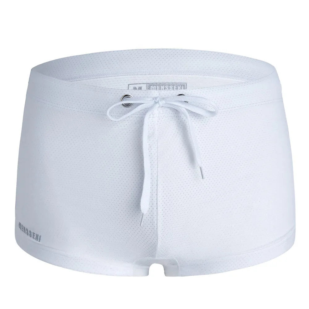 Men's low waist swim trunks in stretch nylon on a man, showing elastic waistband and boxer-style cut.