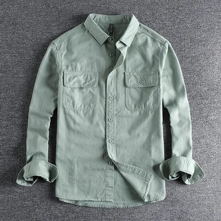 Man wearing a loose-fit grey cardigan-style overalls shirt with long sleeves.