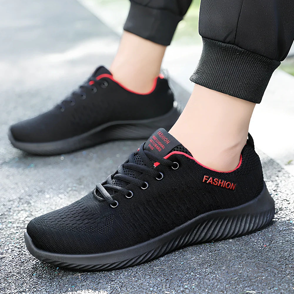 Men's black mesh sports shoes with red accent details and flexible PVC sole construction