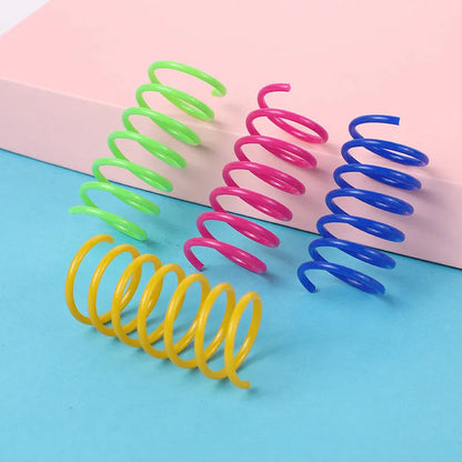 Assortment of colourful plastic coil spring toys for cats on a plain surface.