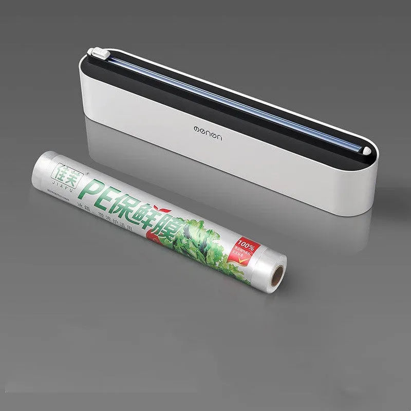 Black plastic cling film cutter and dispenser unit mounted on a refrigerator door.