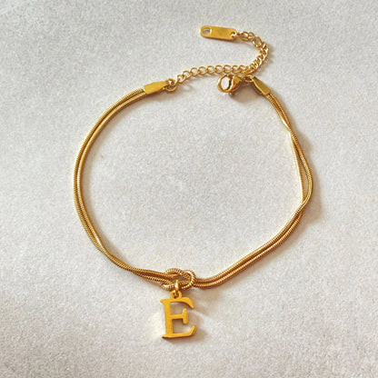 Elegant letter charm bracelets for women in gold and silver tones, featuring a delicate snake chain design and personalised letter charms.