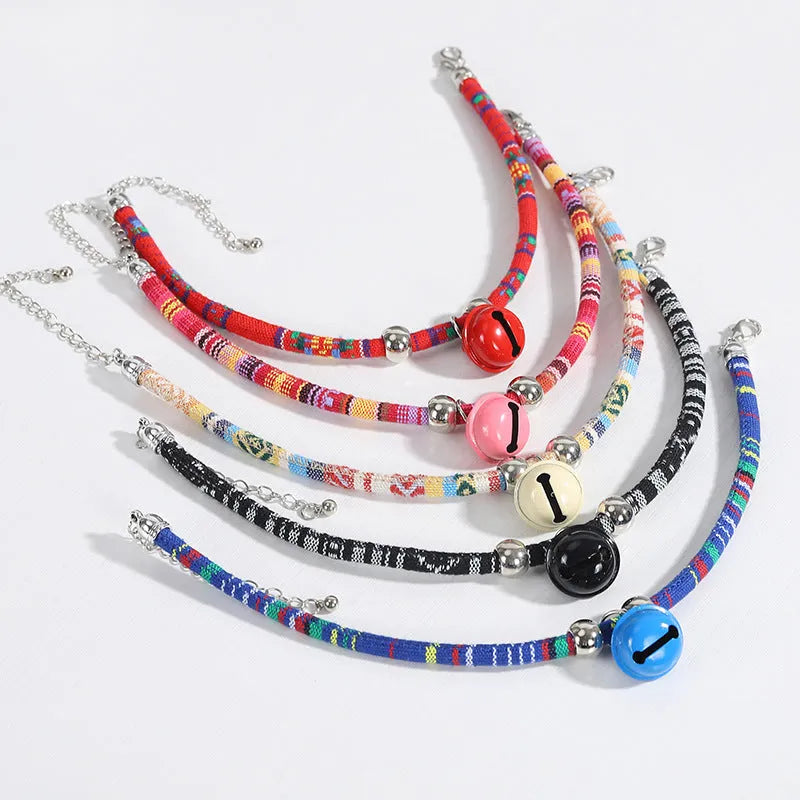 Coloured ethnic pattern adjustable dog collar with metal bell and reflective strip on a nylon strap.