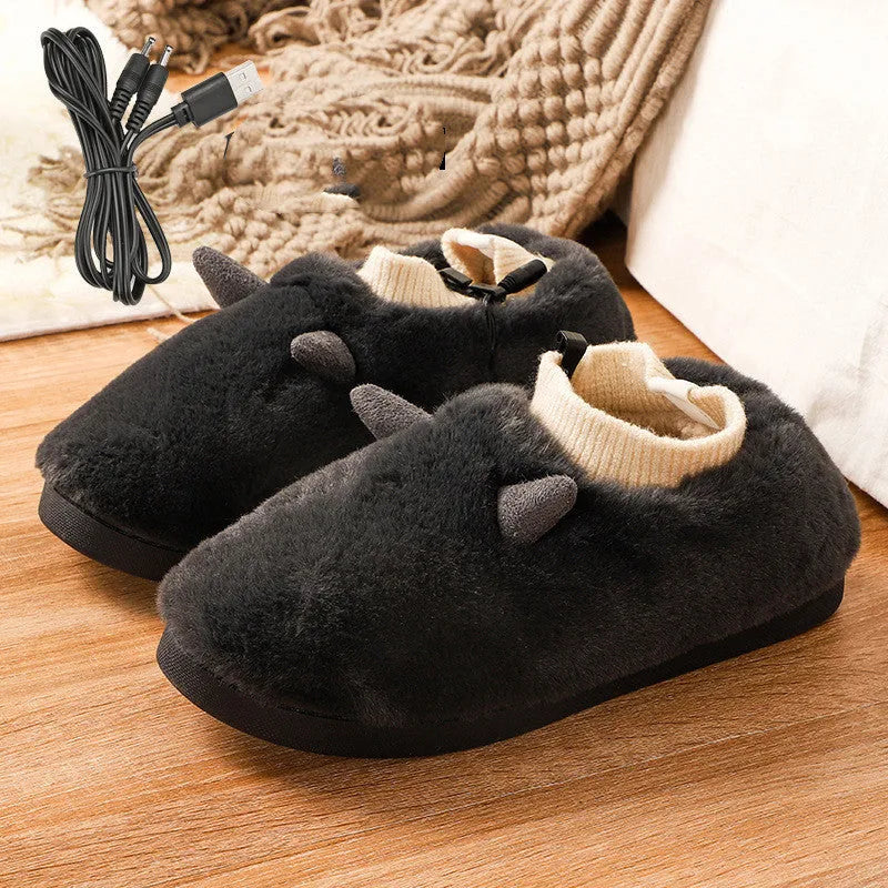 USB heating slippers in black plugged into a laptop, showing the cable and soft velvet upper.