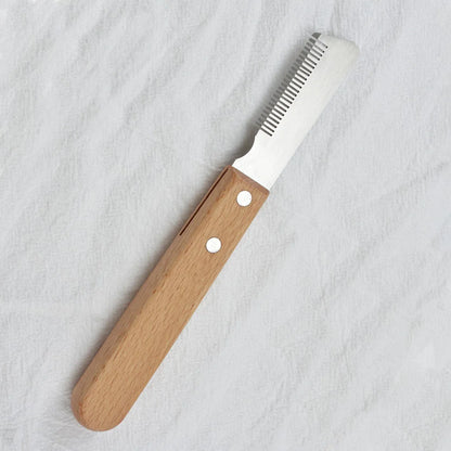 Dog stripping comb grooming tool with wood handle and metal blade for removing hair.