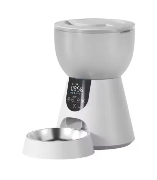 Automatic cat feeder with built-in camera on kitchen floor next to food bowl.