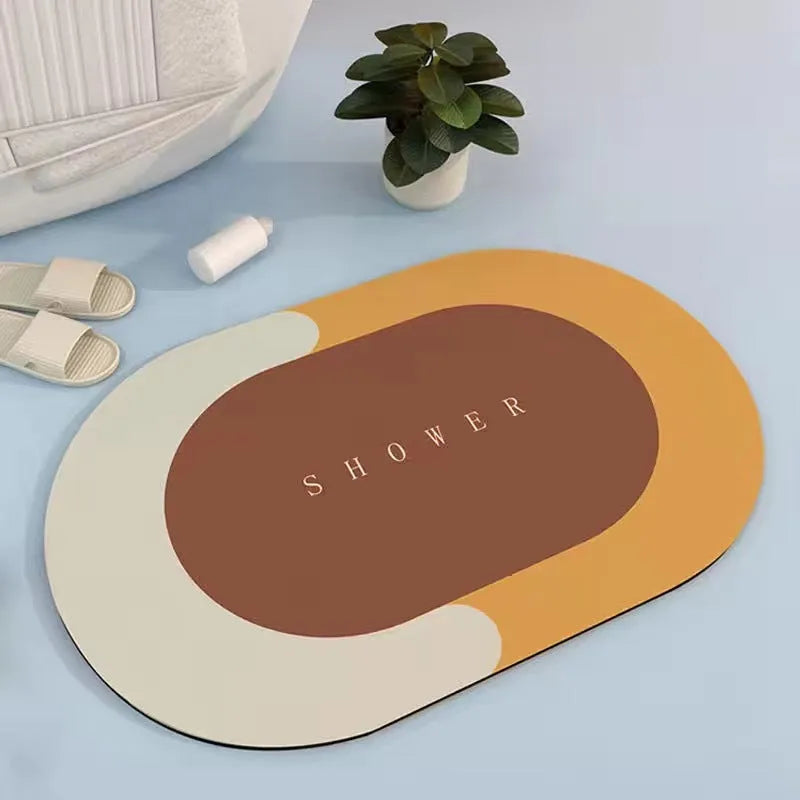 Oval grey bath mat with non-slip rubber bottom on a tiled floor, showing absorbent fabric surface