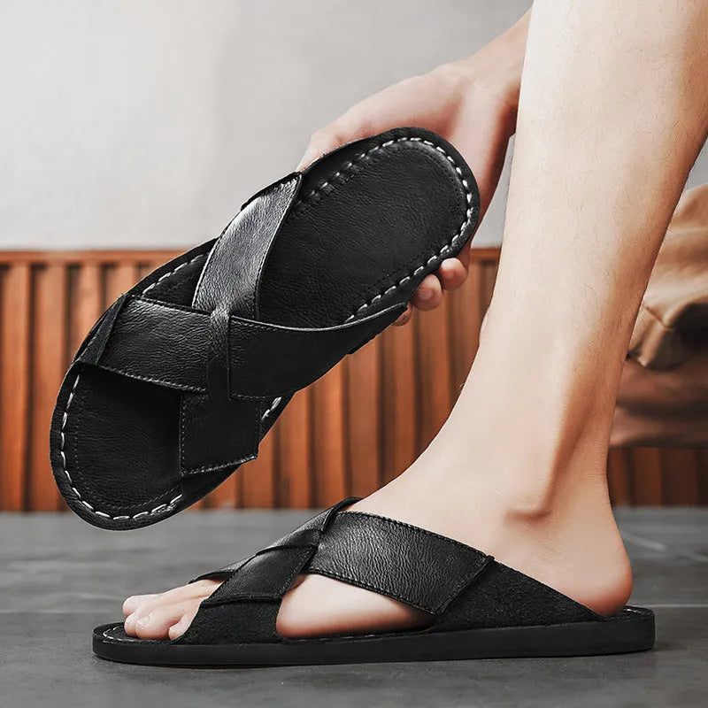 Men's black frosted pigskin leather slip-on sandals with a sewn rubber sole on a beach background.