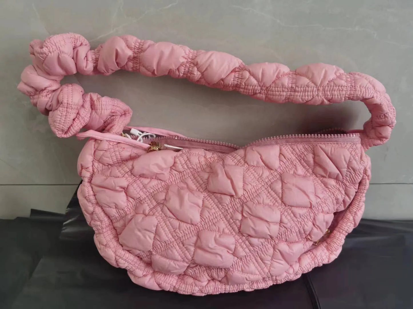 Women's light grey nylon underarm messenger bag with adjustable long strap, shown worn crossbody.