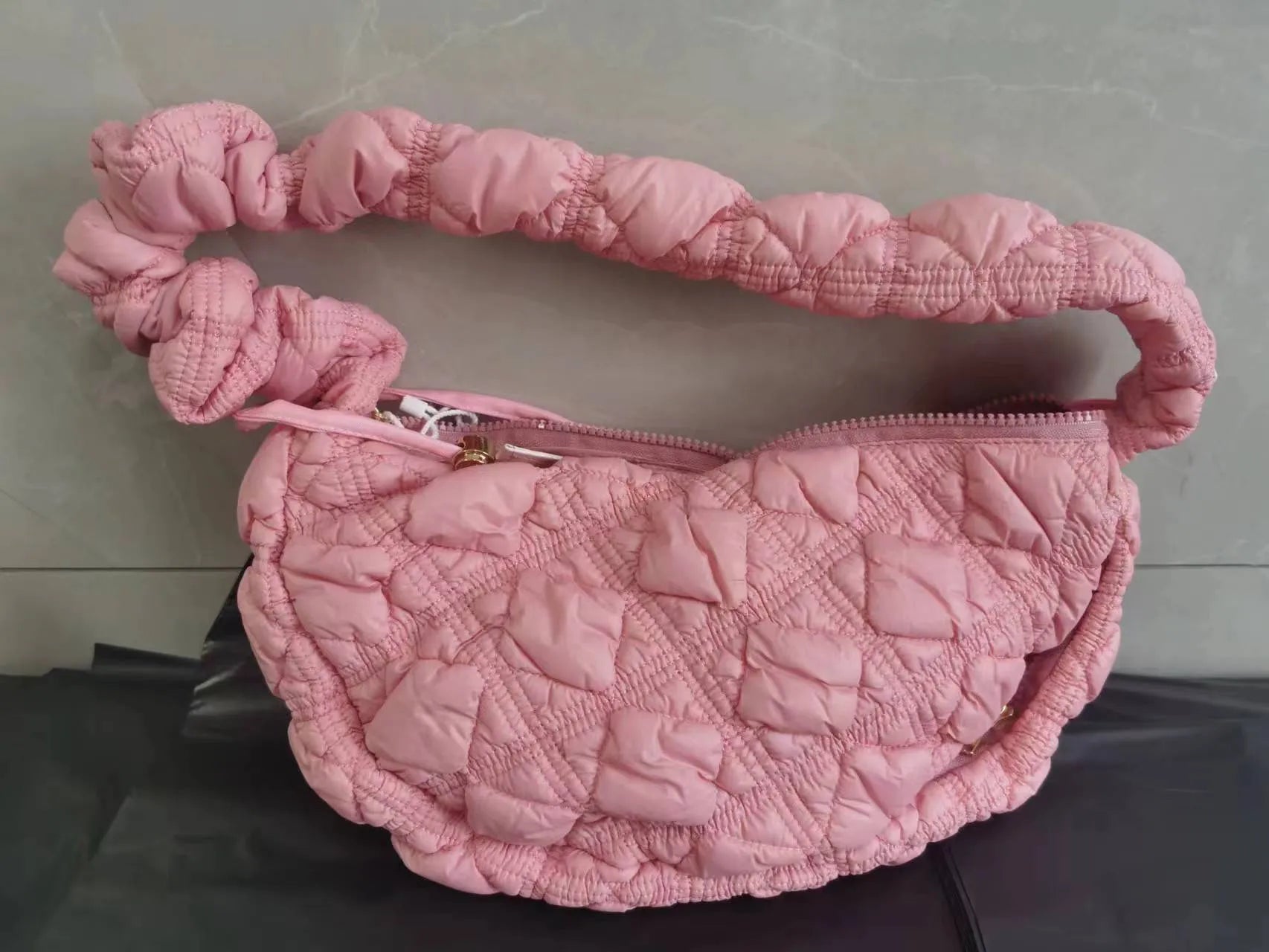 Women's light grey nylon underarm messenger bag with adjustable long strap, shown worn crossbody.