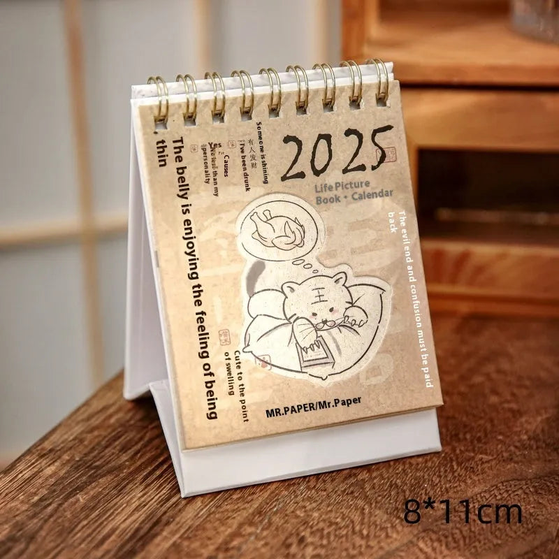 Set of four different themed 2025 mini paper desk calendars on a desk.
