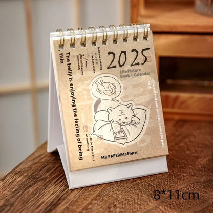 Set of four different themed 2025 mini paper desk calendars on a desk.