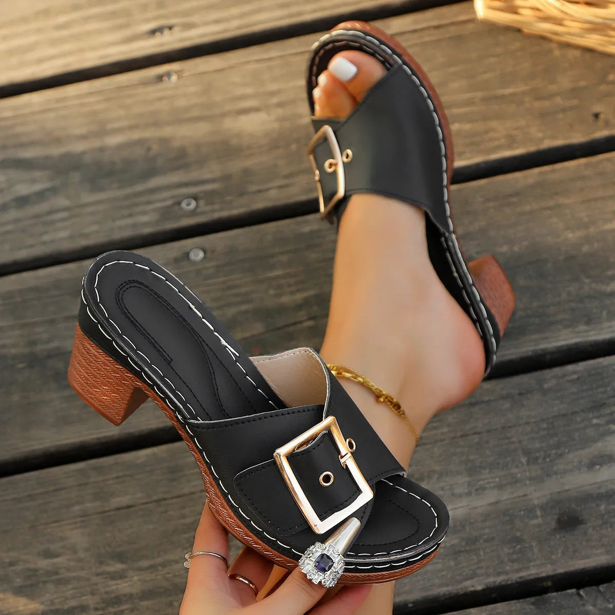 Women's black chunky heel slippers with a metal buckle and round toe, on a rubber sole