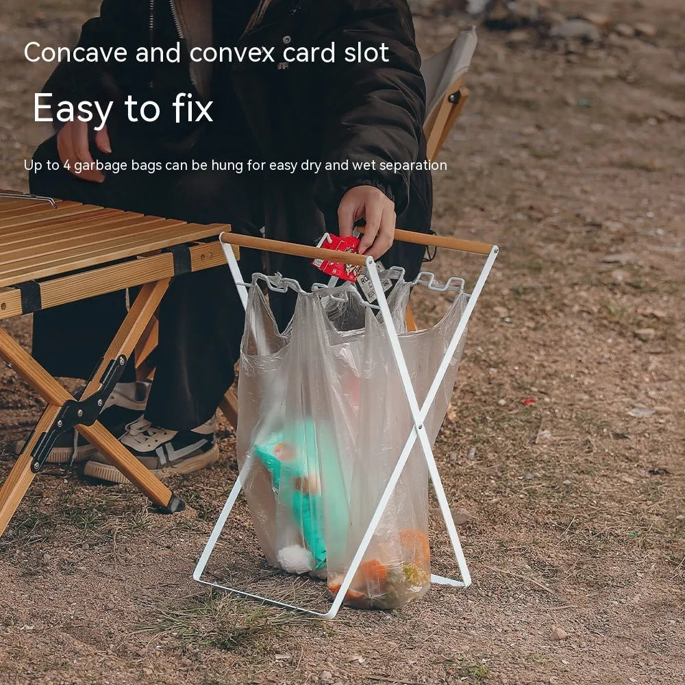 Black outdoor folding trash rack with wooden handle, holding a waste bag.