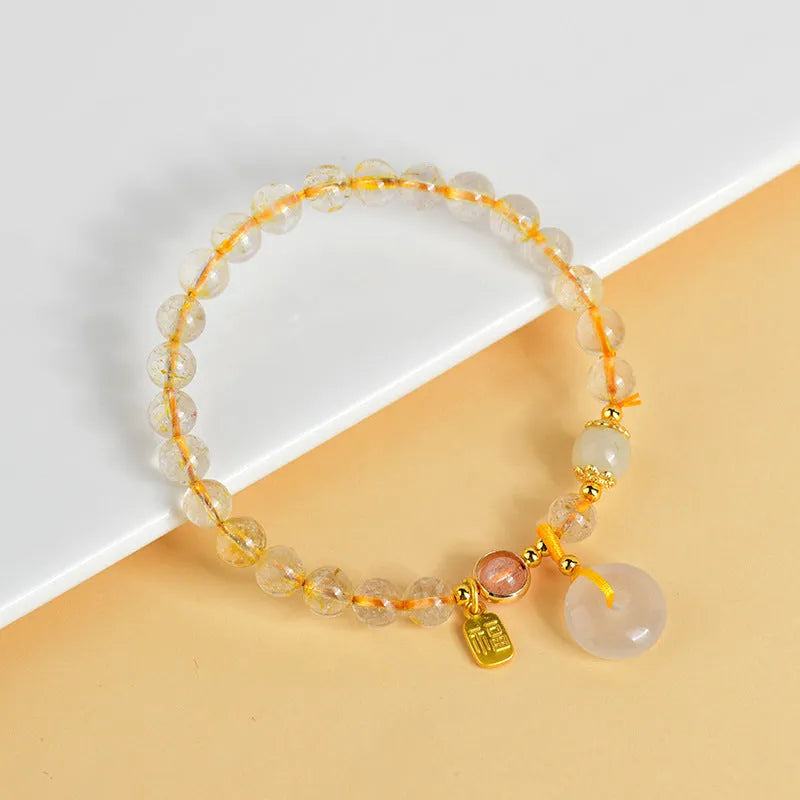 Gold rutilated quartz crystal bracelet with geometric peace buckle pendant and safety clasp