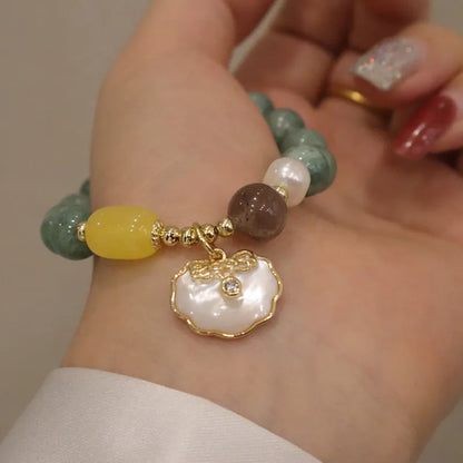 Light green jade bead bracelet with a shell charm and adjustable metal clasp.