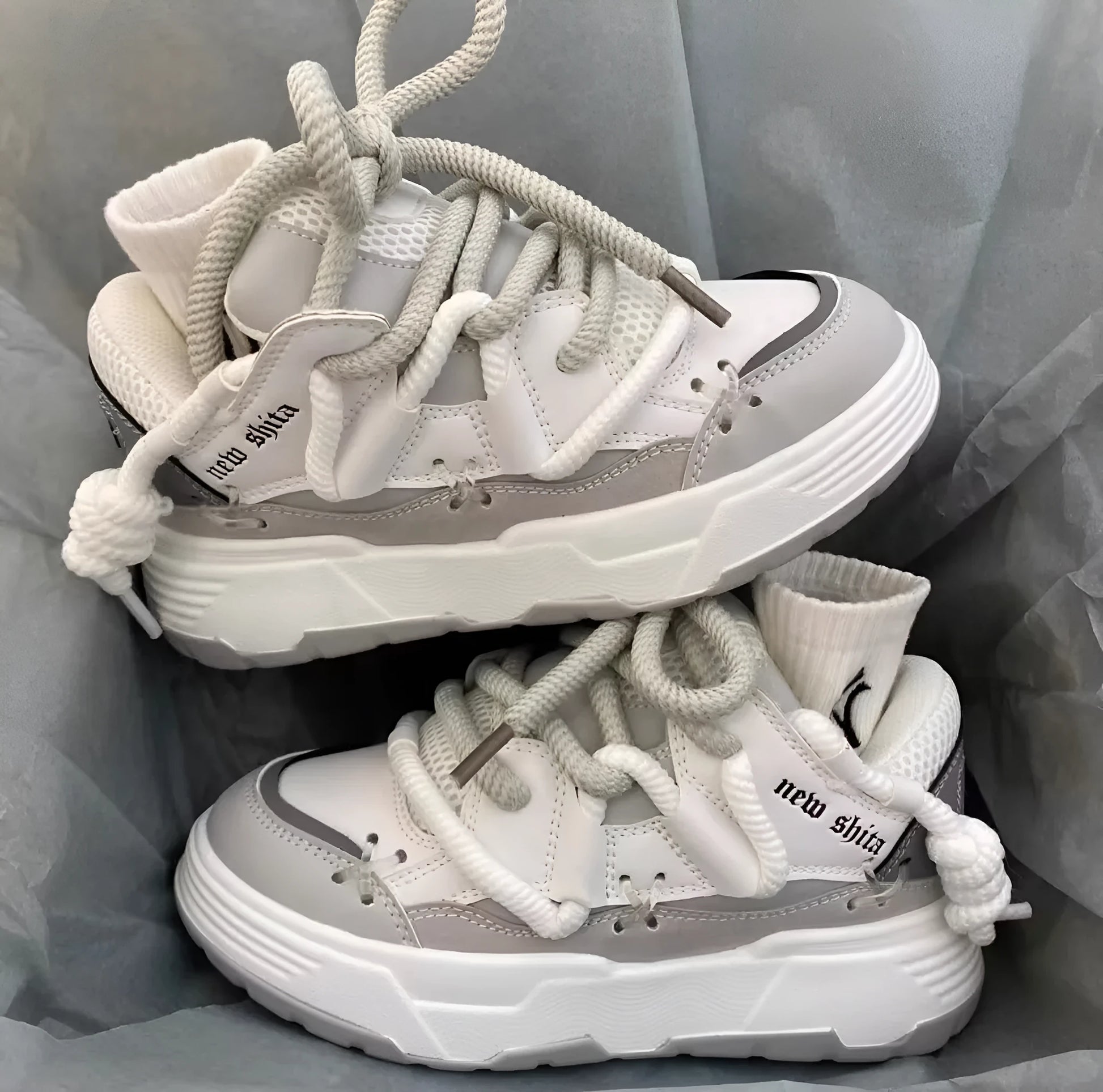 Women's grey thick-soled retro sneakers with lace-up front and chunky rubber platform sole on a wooden floor.