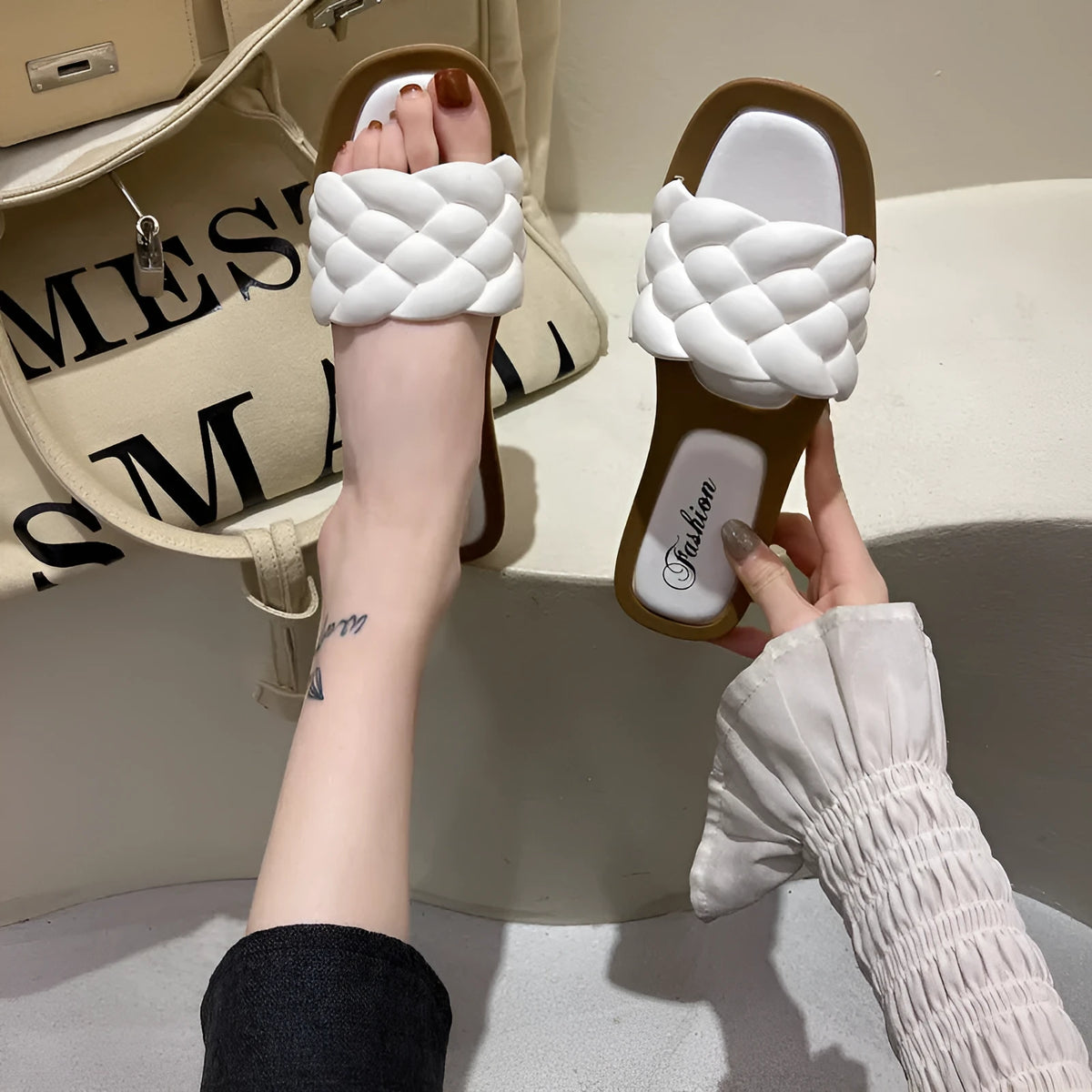Women's white PVC beach sandals with a thick, patterned sole on a sandy background.