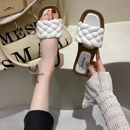 Women's white PVC beach sandals with a thick, patterned sole on a sandy background.