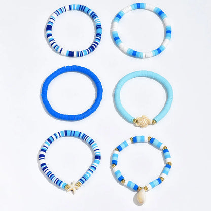Six handmade Bohemian Blue polymer clay bracelets with geometric shell designs arranged together