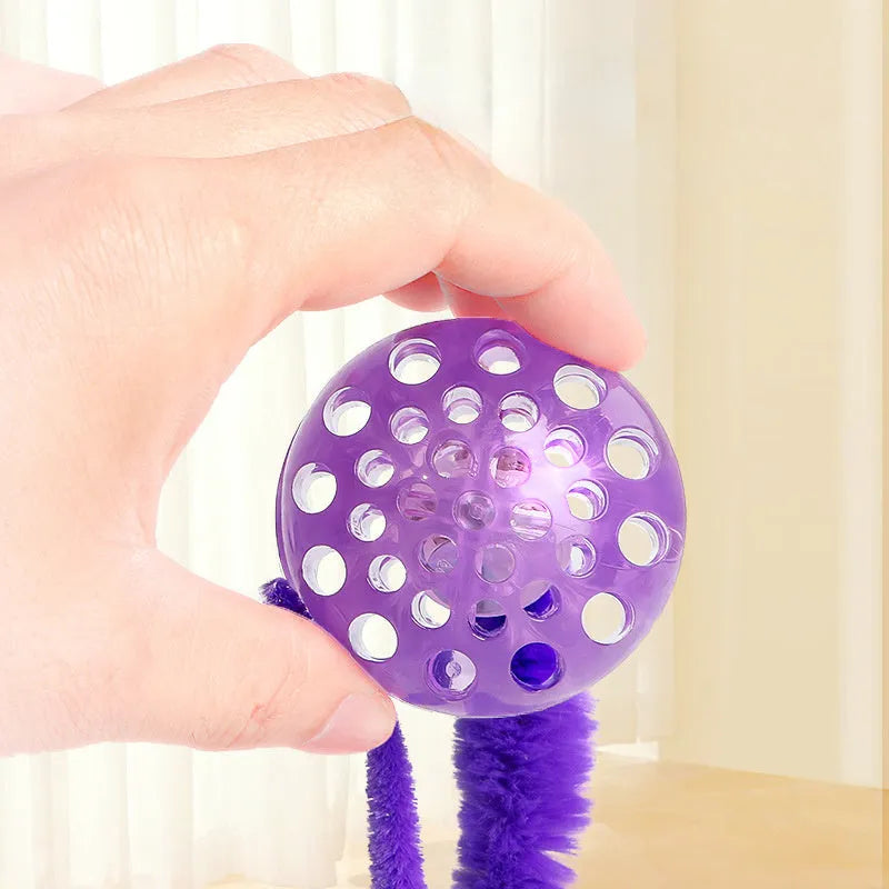 Green interactive cat toy with a bouncy ball and a long worm-shaped tail on a plain background.