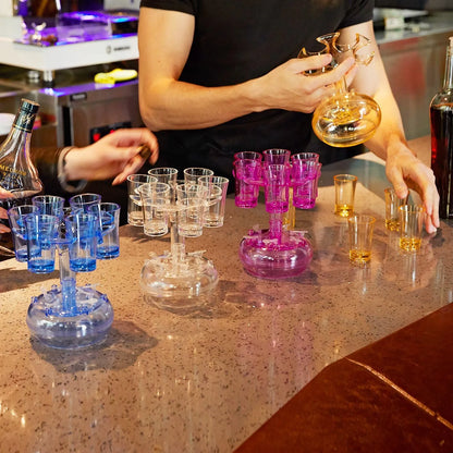 Transparent six-shot glass dispenser rack with individual covers on a wooden bar