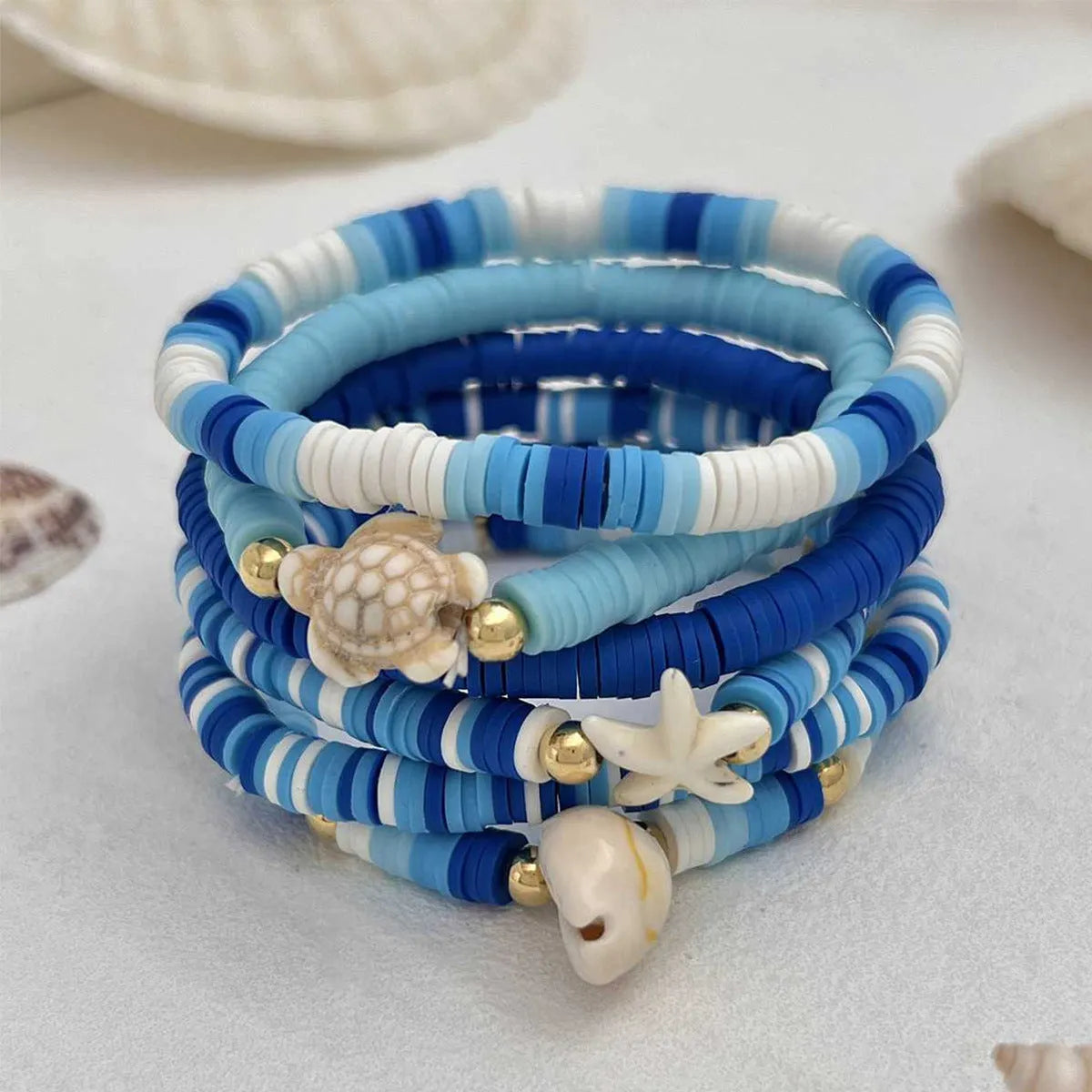 Six handmade Bohemian Blue polymer clay bracelets with geometric shell designs arranged together