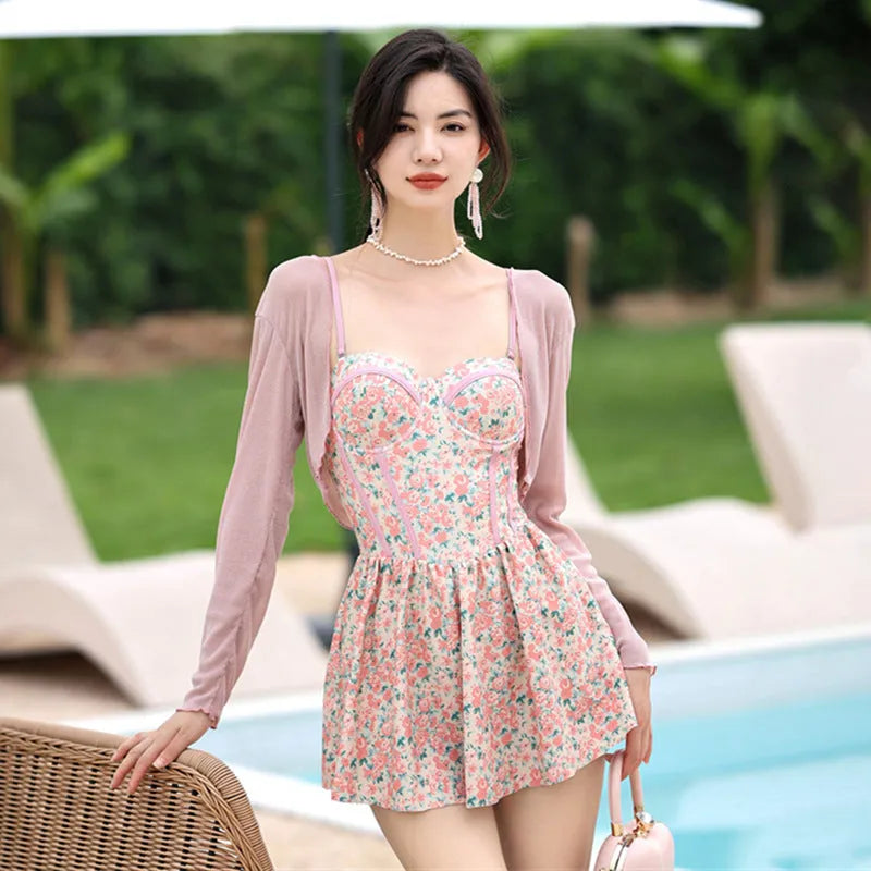Women's pink floral one-piece jumpsuit swimsuit with suspender straps on a hanger.