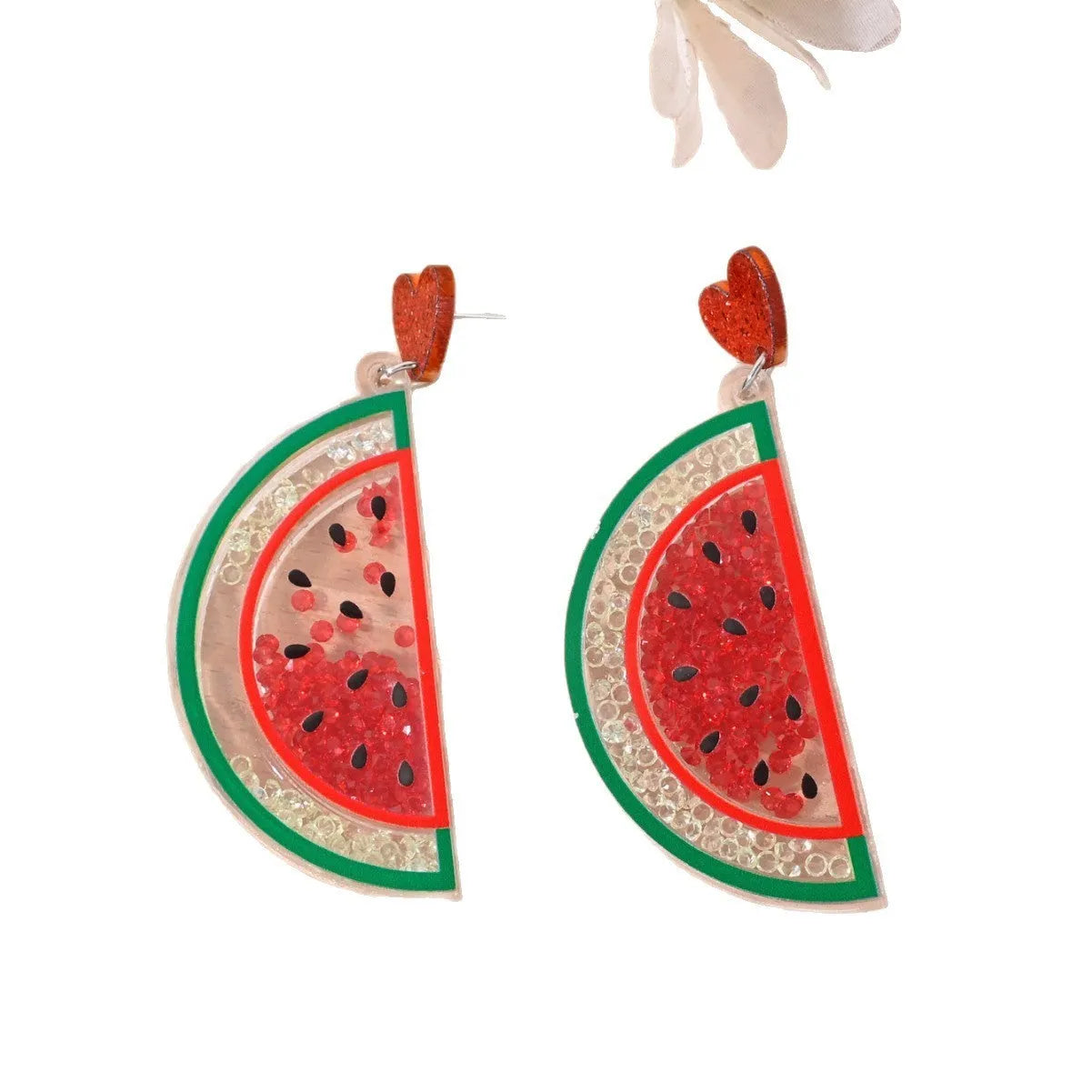 A pair of colourful acrylic earrings shaped like a strawberry and a cherry on a woman's ear.