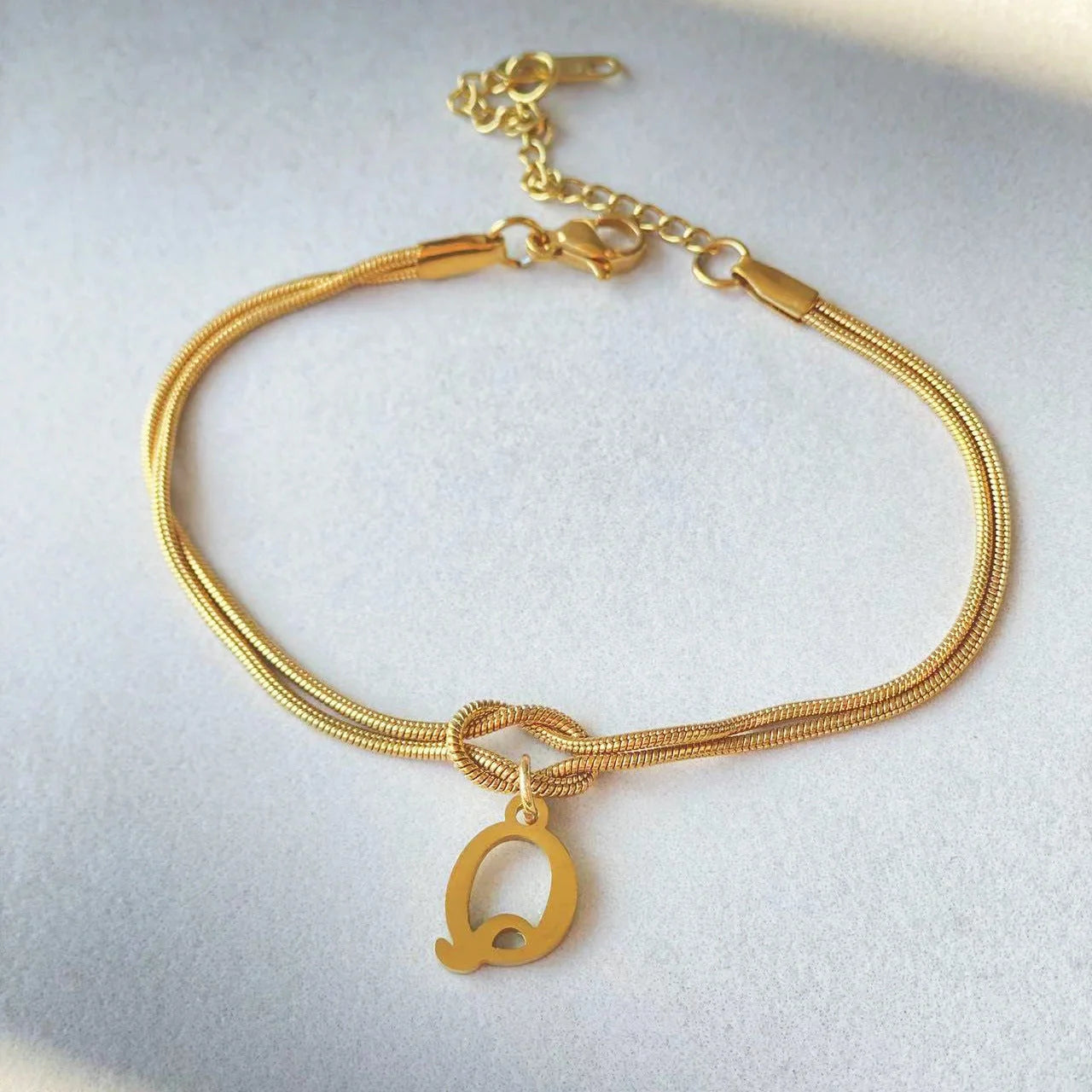 Elegant letter charm bracelets for women in gold and silver tones, featuring a delicate snake chain design and personalised letter charms.