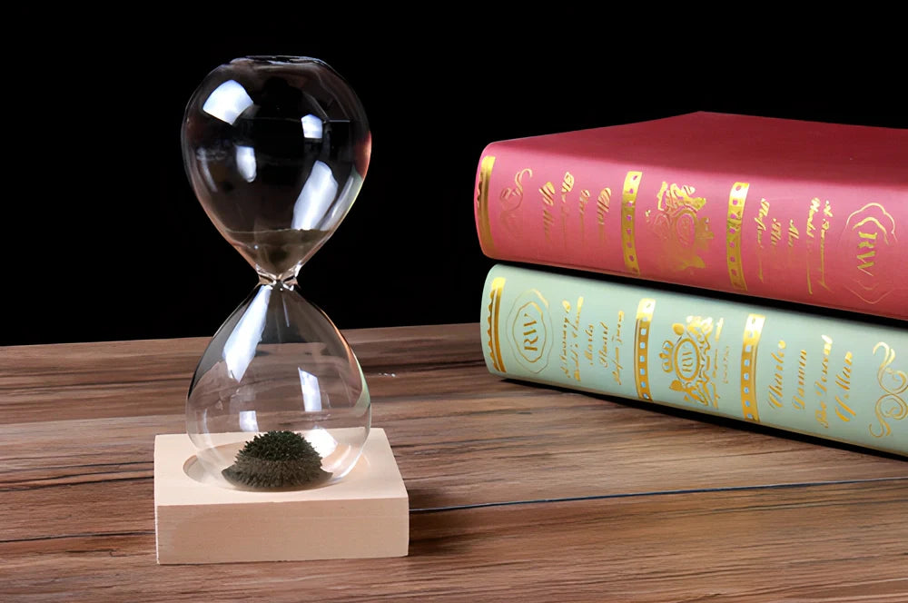 Captivating magnetic hourglass with a solid wood base and glass chamber, creating a mesmerizing display of temporary stalagmites.