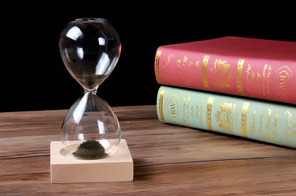 Captivating magnetic hourglass with a solid wood base and glass chamber, creating a mesmerizing display of temporary stalagmites.