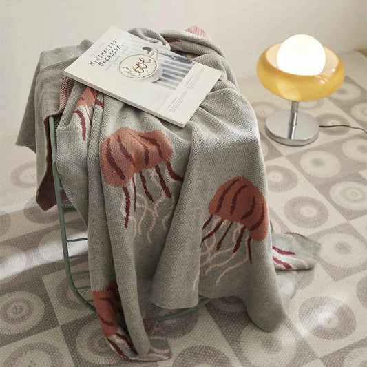 Cosy jellyfish-patterned cotton knit throw blanket in green and grey colours, showcasing its soft, plush texture and unique design.