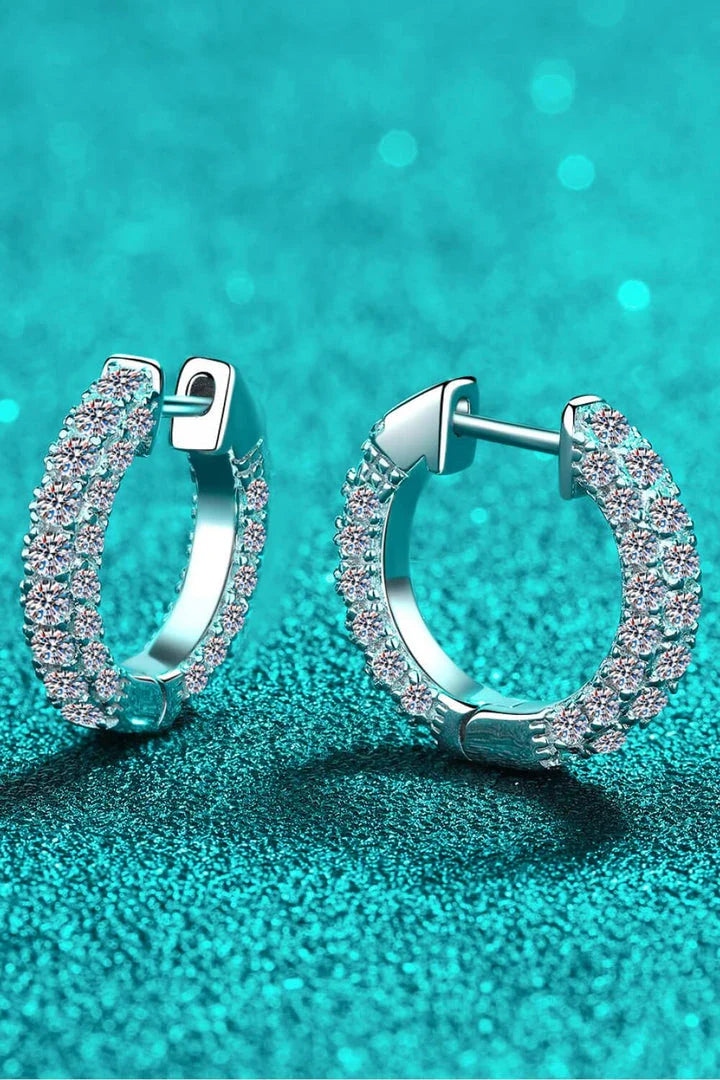 Pair of elegant sterling silver huggie earrings adorned with dazzling moissanite stones, showcasing a minimalist and sophisticated design.