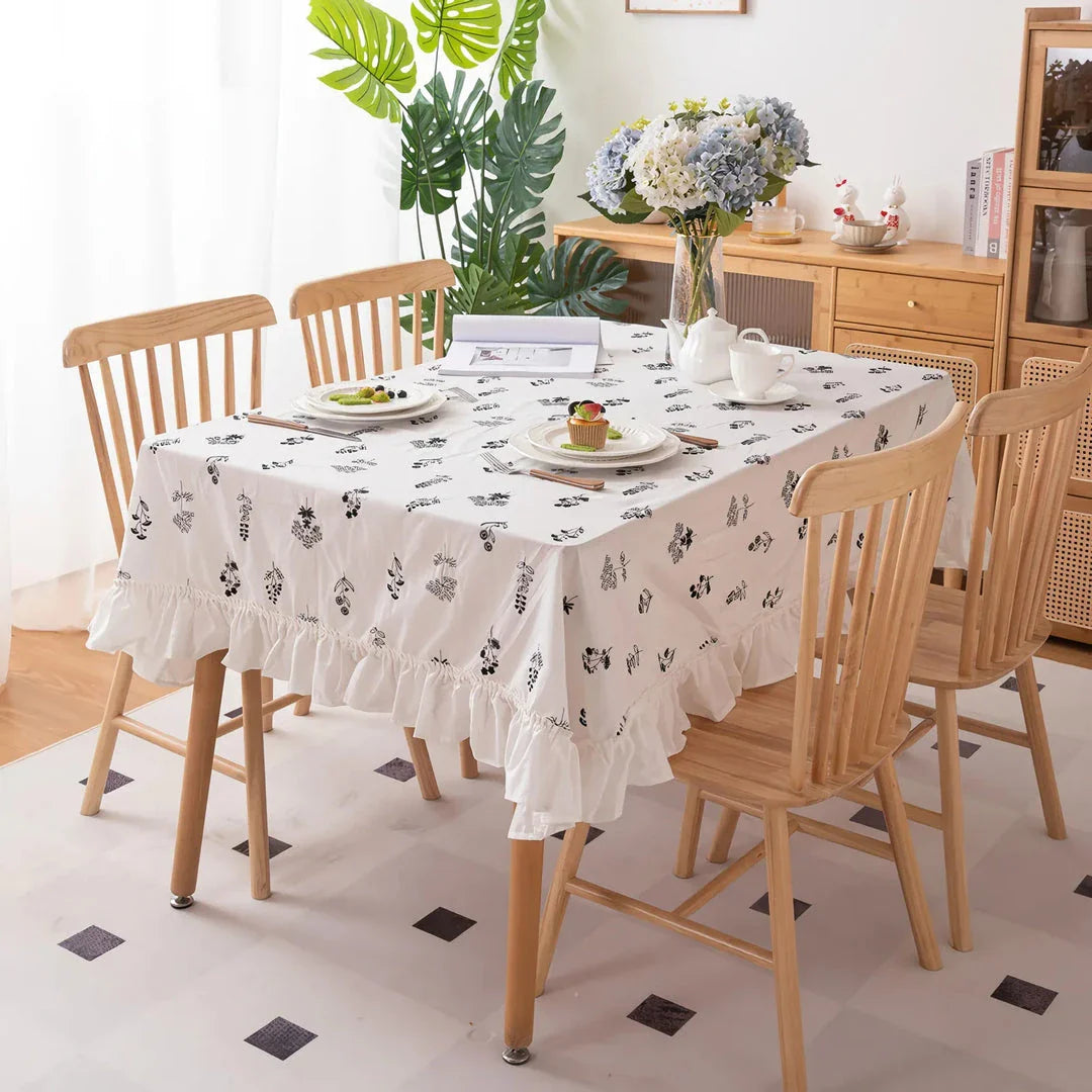 A high-quality cotton tablecloth with elegant floral embroidery and ruffled edges, creating a refined and charming dining experience.