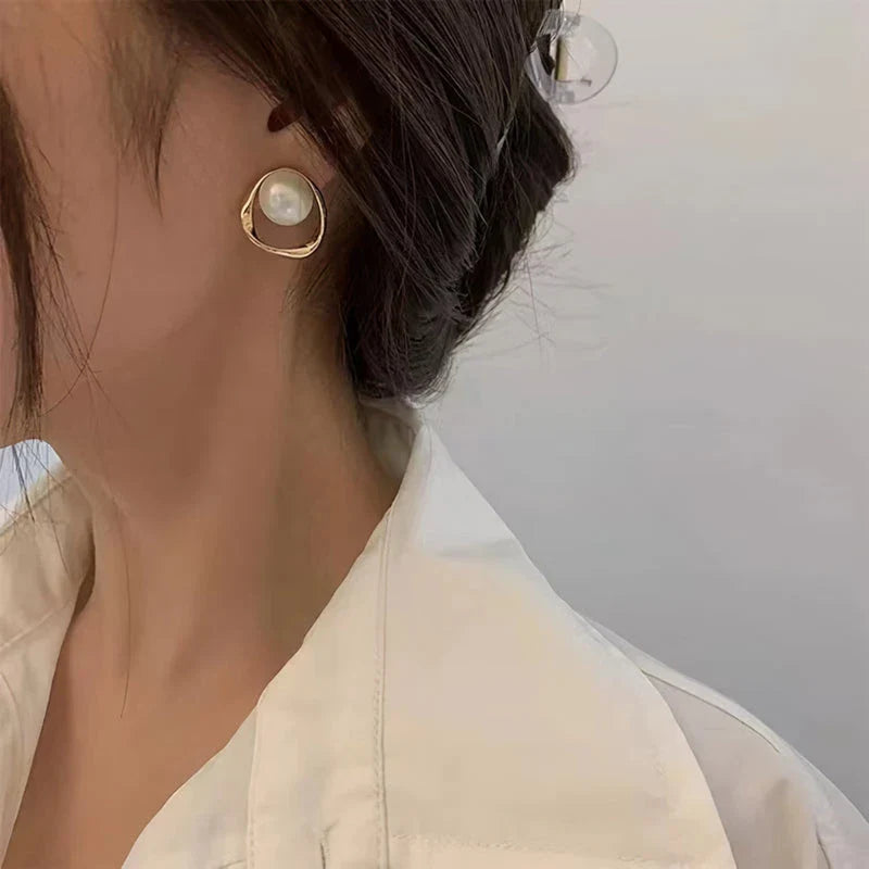 Elegant gold-coloured simulated pearl stud earrings with a distinctive geometric design