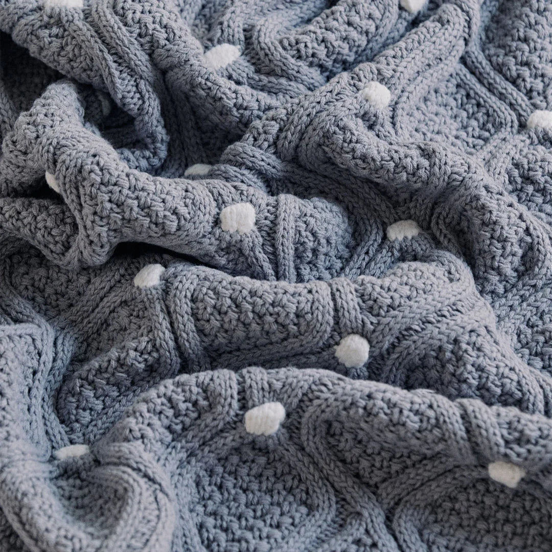Cosy chunky knit blanket with charming pompoms in multiple sizes and colours for elegant home décor