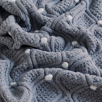 Cosy chunky knit blanket with charming pompoms in multiple sizes and colours for elegant home décor