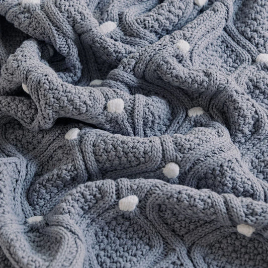 Cosy chunky knit blanket with charming pompoms in multiple sizes and colours for elegant home décor