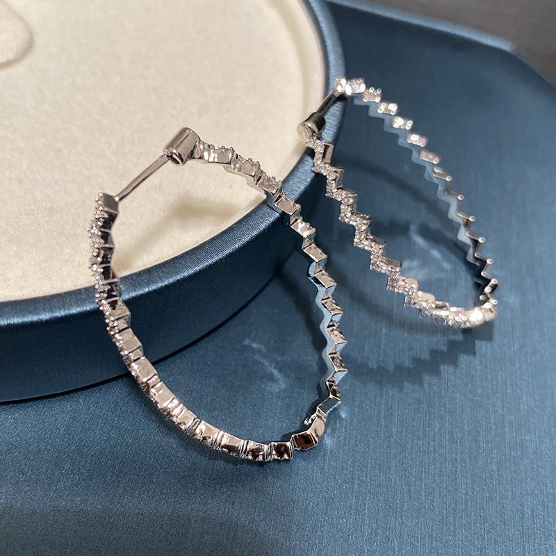 A pair of elegant sterling silver geometric earrings with a captivating wave-like pattern, inspired by the latest fashion trends in Japan and South Korea.