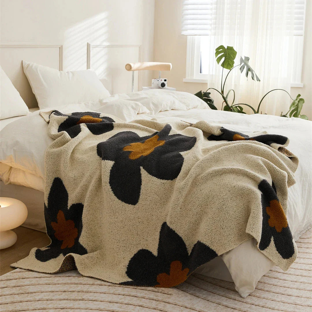 Cosy floral knitted throw blanket in red, grey, and orange shades - a high-quality microfibre accessory for year-round comfort and style