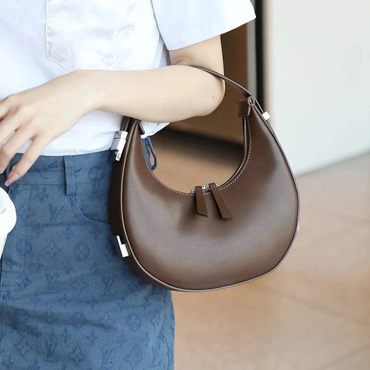 Elegant leather shoulder bag with a unique half-moon shape, designed for the modern British woman