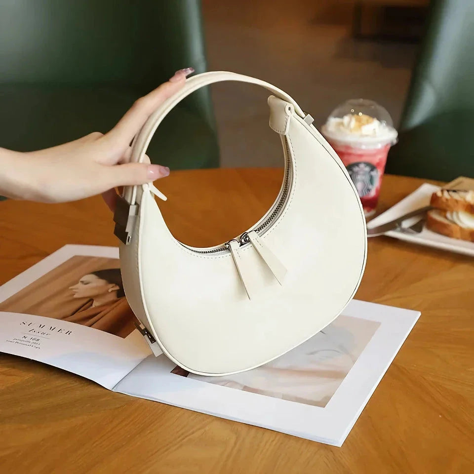 Elegant leather shoulder bag with a unique half-moon shape, designed for the modern British woman